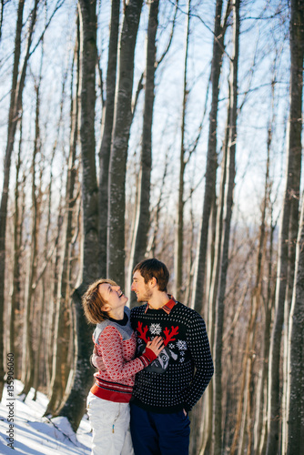 Happy smiling couple in stylish sweaters walks in spring forest