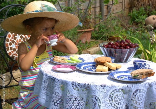 Canvas Print Time for tea! Pretty child having a grown-up summer tea-time in the garden