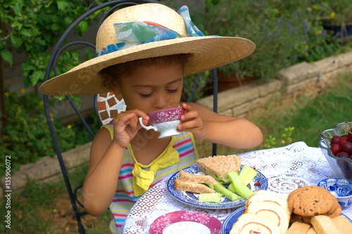 Fotografija Time for tea! Pretty child having a grown-up summer tea-time in the garden