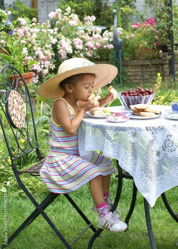 Fotografía Time for tea! Pretty child having a grown-up summer tea-time in the garden
