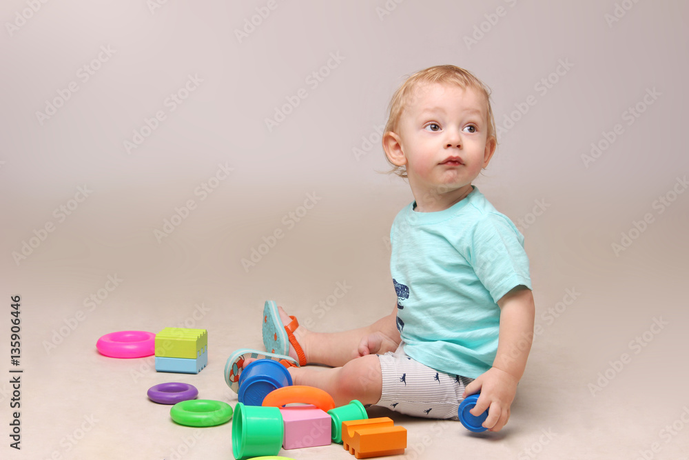 Studio shot of an adorable baby boy sitting on the floor and playing with some toys. Studio shot of an adorable baby boy sitting on the floor and playing with some toys.
