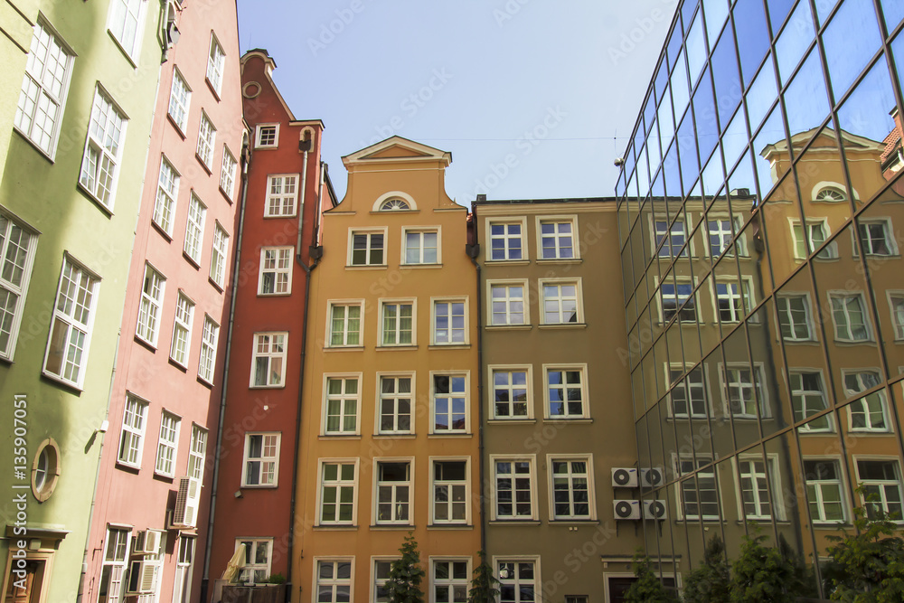 Colorful tenement houses reflected in windows of modern building, Gdansk, Poland