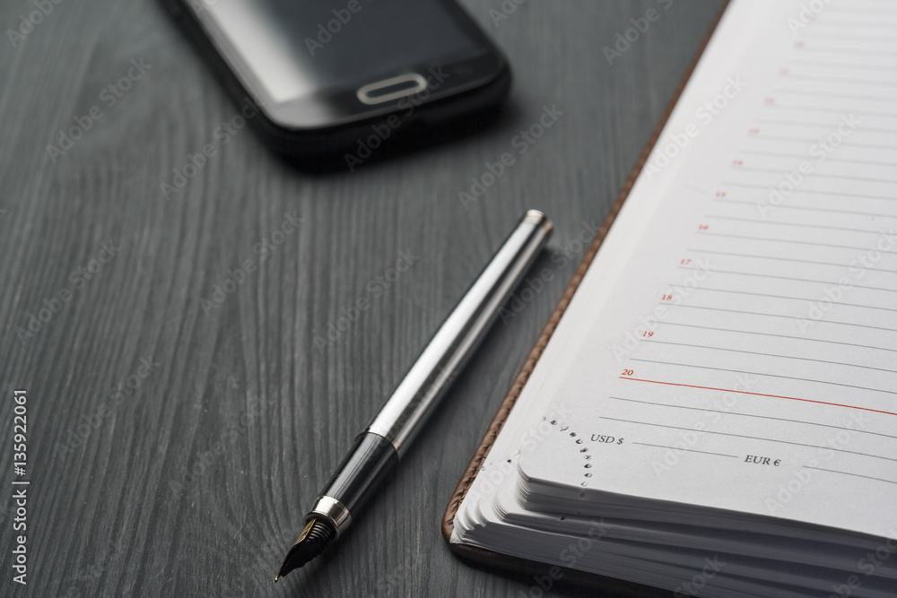 ll life, business, education concept. Office supplies, blank screen smartphone, gift box, watch, notepad, diary and pens on a table. ll life, business, education concept. Office supplies, blank screen smartphone, gift box, watch, notepad, diary and pens on a table.