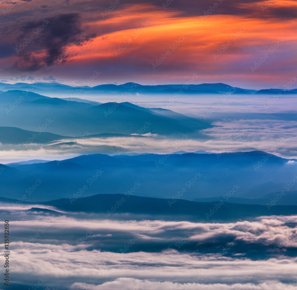  Magical landscape in the mountains at sunset. View of  colorful sky with clouds and foggy hills covered by forest. 