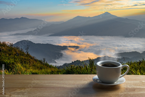 Morning cup of coffee with mountain background at sunrise