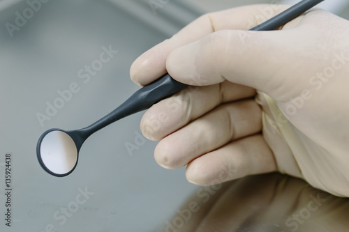 Close up of dentist hand with dental mirror