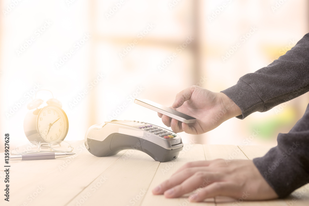 Fototapeta premium Mobile payments concept with EDC machine or credit card terminal with computer laptop and glasses. Warm toning effect.