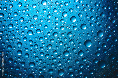 Water drops on blue glass surface texture.