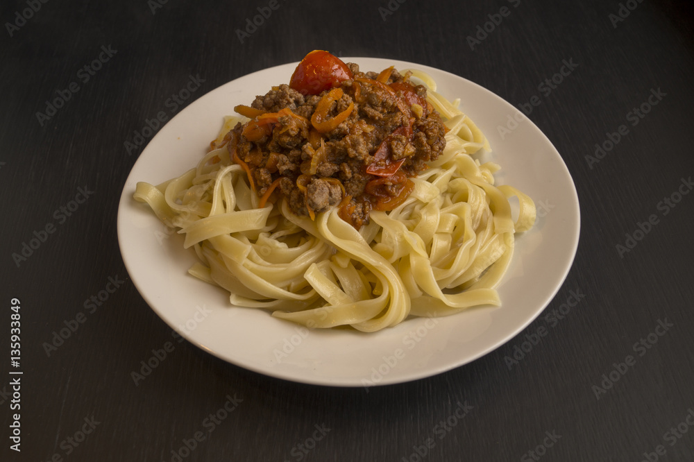 Italian pasta Bolognese in the white plate on black background