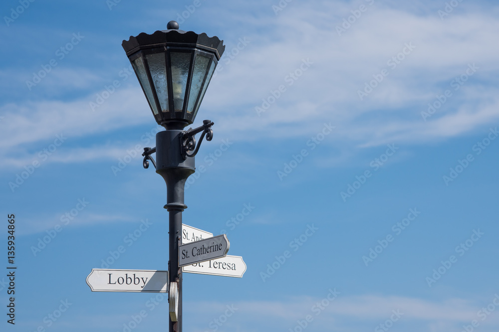 City lamp with street sign on blue sky background.