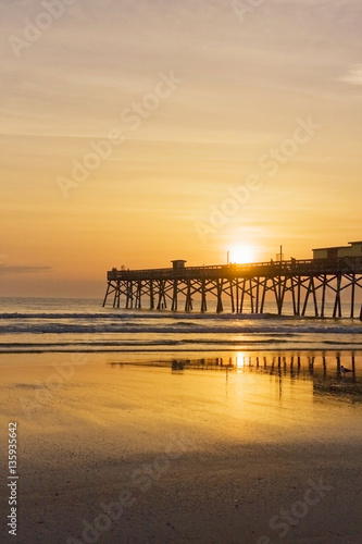 Florida sunrise. Atlantic ocean sunrise in Daytona beach, Florida, USA. Seascape with rising sun over wooden pier.