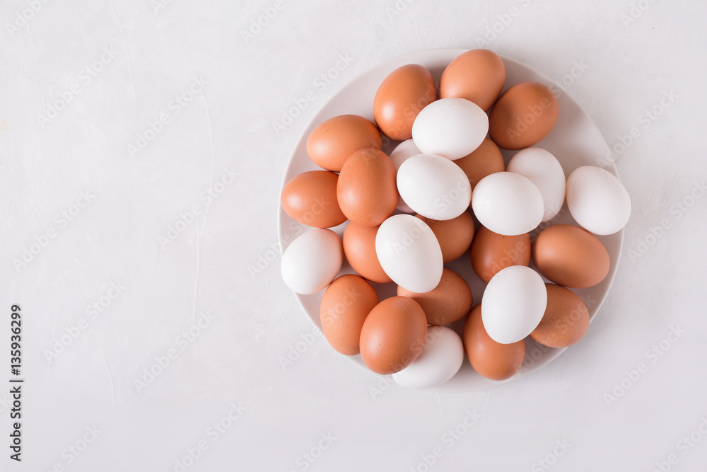 Brown and white eggs on a white plate on a white background. Eggs. Easter photo concept. Copyspace Brown and white eggs on a white plate on a white background. Eggs. Easter photo concept. Copyspace