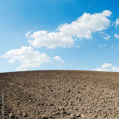 spring plowed field and blue sky with clouds