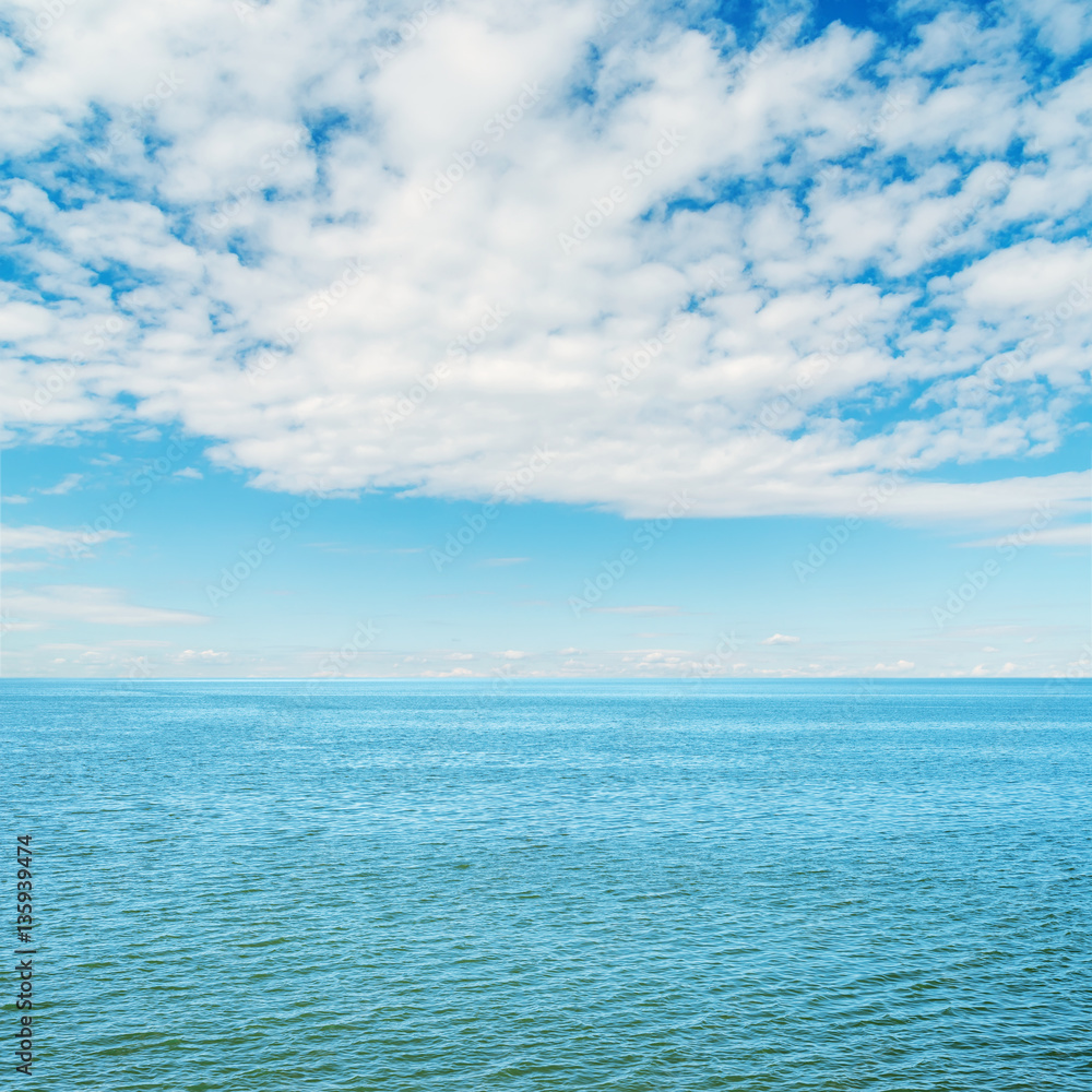 blue sea and clouds in blue sky over it