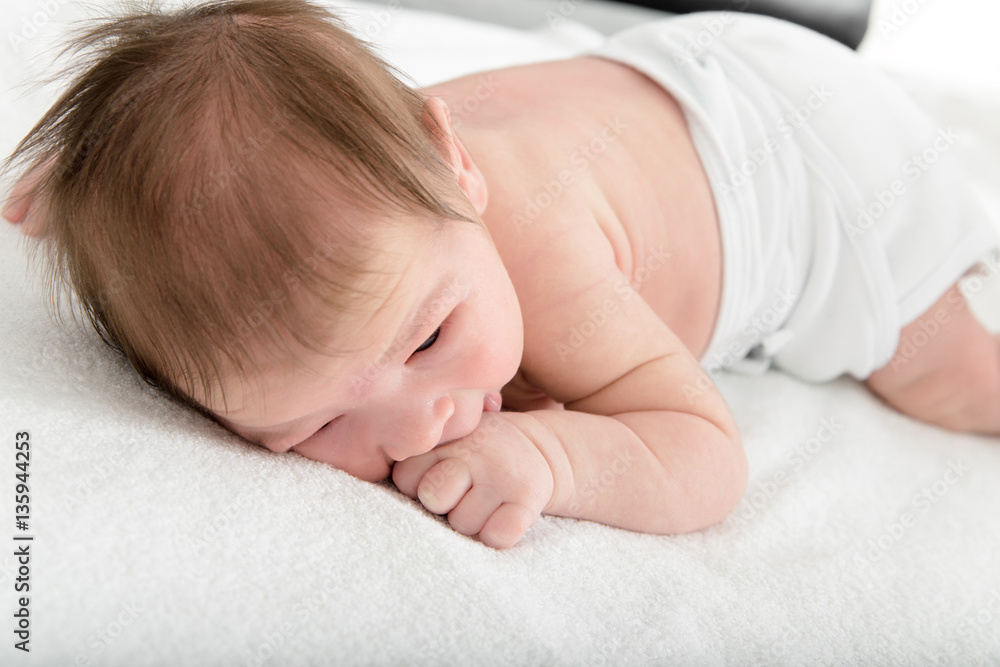 Adorable sleepy newborn baby lying on soft bed Adorable sleepy newborn baby lying on soft bed