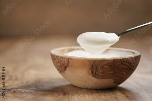 eating organic yogurt with spoon from wood bowl, 4k photo