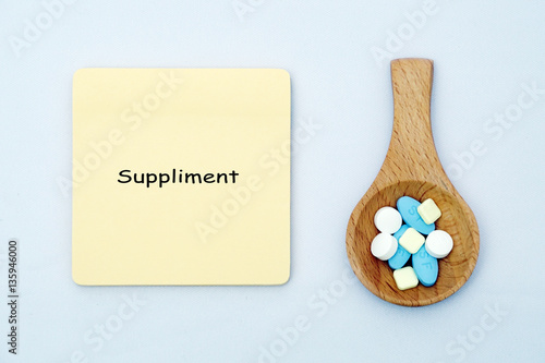 A medical pills in a spatula with a note written SUPPLIMENT on isolated white background. Medical, health care, education, and information concept photo