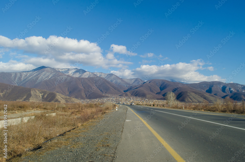 Landscape of asphalt road going off into the mountain passes through the trees, villages and forest places. or rural places of Azerbaijan at sunset