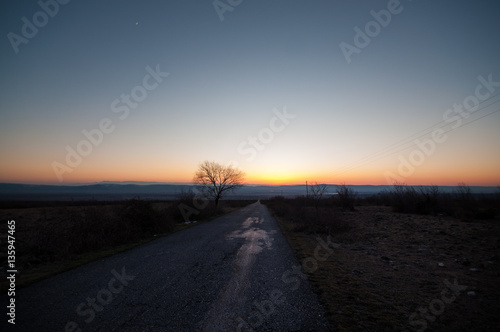 Autumn or winter landscape with road and trees. The gold light beams sunset. On a background of mountains and the sky with clouds. Azerbaijan Caucasus