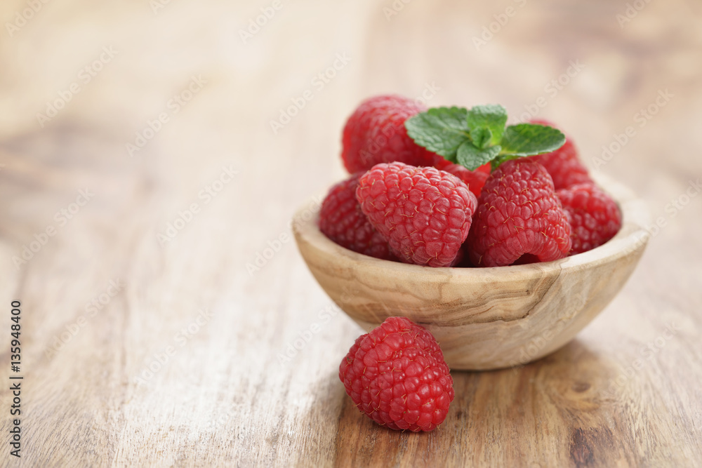 wood bowl full of ripe raspberries with mint leaves on old wooden table, with copy space wood bowl full of ripe raspberries with mint leaves on old wooden table, with copy space