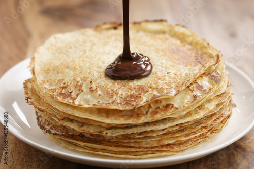 premium dark chocolate pour on freshly made blinis or crepes, simple sweet food photo