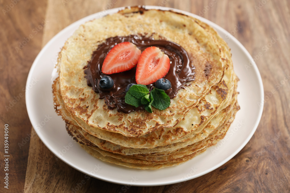 fresh blinis or crepes with melted dark chocolate and berries, shallow focus fresh blinis or crepes with melted dark chocolate and berries, shallow focus