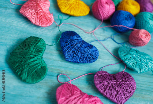 Multicolored Hearts with a balls of thread on blue wooden backgr