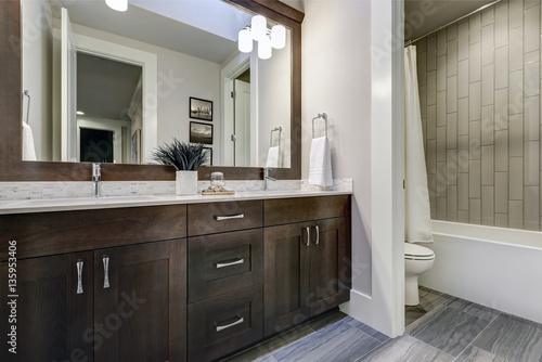 White and brown bathroom boasts a nook filled with double vanity
