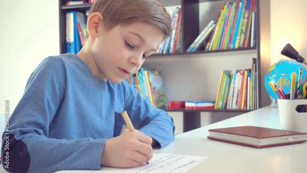 Cute school boy doing homework at desk in his room Cute school boy doing homework at desk in his room