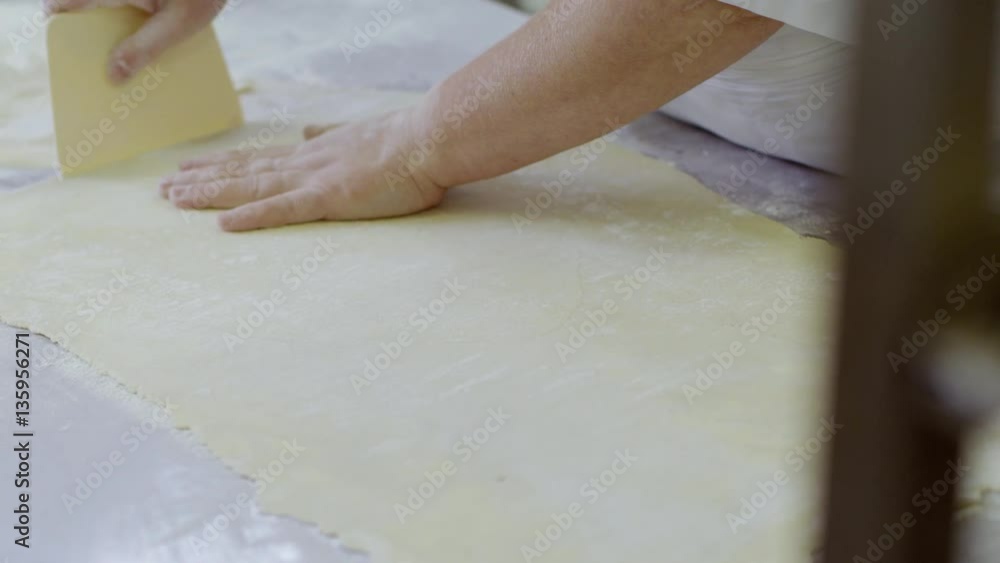 Woman cut off the edges of dough Woman cut off the edges of dough