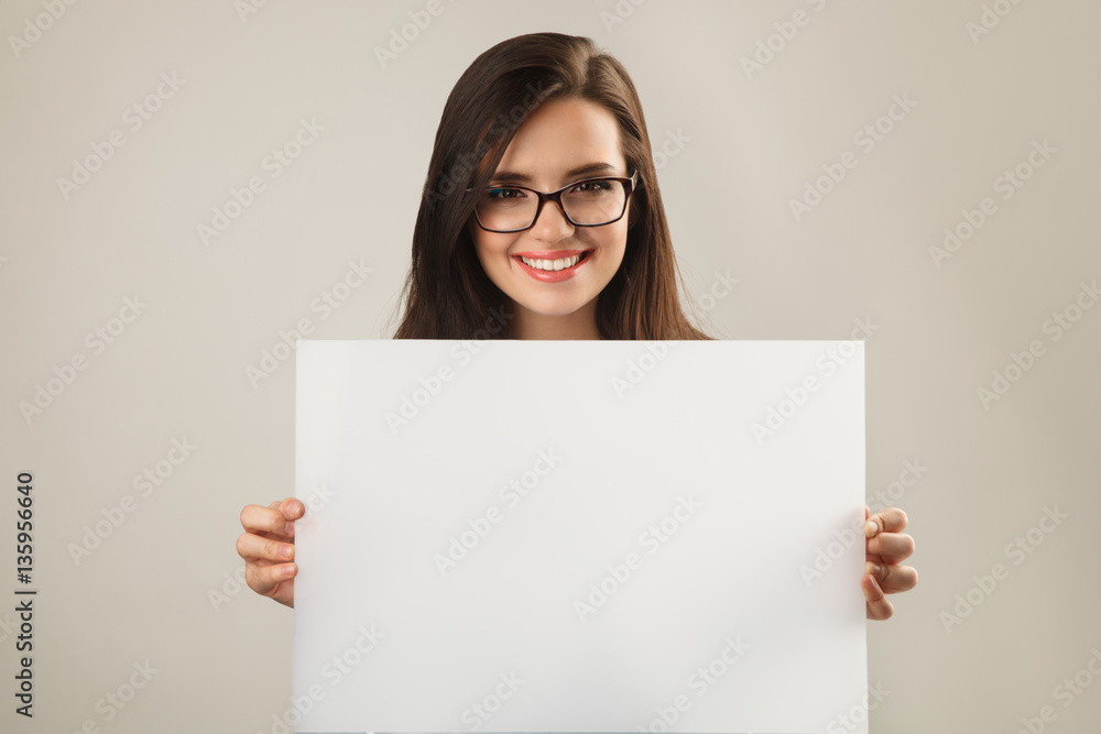 Young beautiful woman in glasses holding white blank board Young beautiful woman in glasses holding white blank board