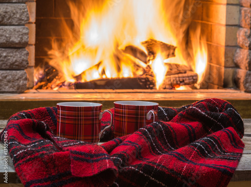 Obraz na plátne Red  cups  and  warm scarf against  the  background of  cozy  fireplace