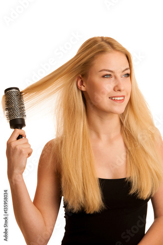 Beautiful blonde woman brushing her hair as a sign og hair care