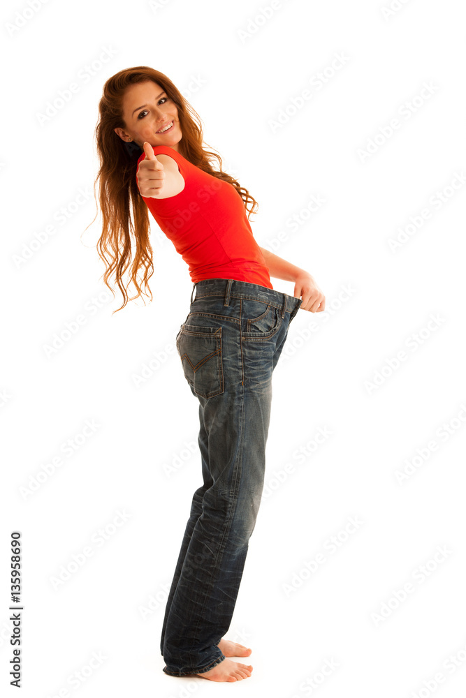 Beautiful young woman holding scale and too big trousers as she Beautiful young woman holding scale and too big trousers as she