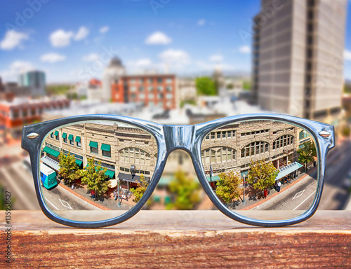  hipster glasses on a park bench or table with a cityscape in th