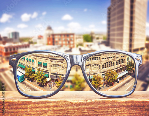  hipster glasses on a park bench or table with a cityscape in the background