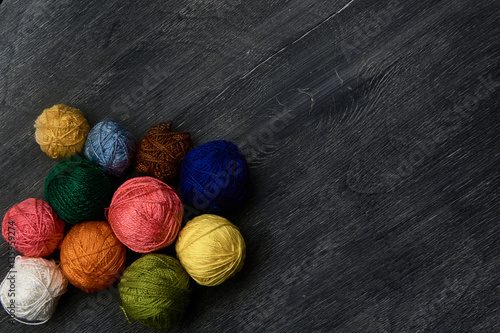 Colorful balls of yarn on wooden background of chalk board.