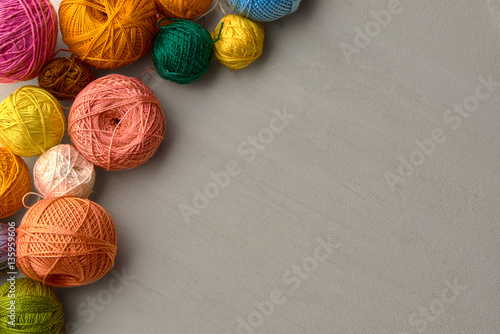Colorful balls of yarn on white wooden background.