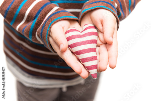 Striped heart in hands of little kid. Isolated on a white background
