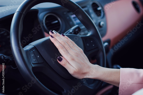 Woman push the button on a steering wheel in car © Iryna