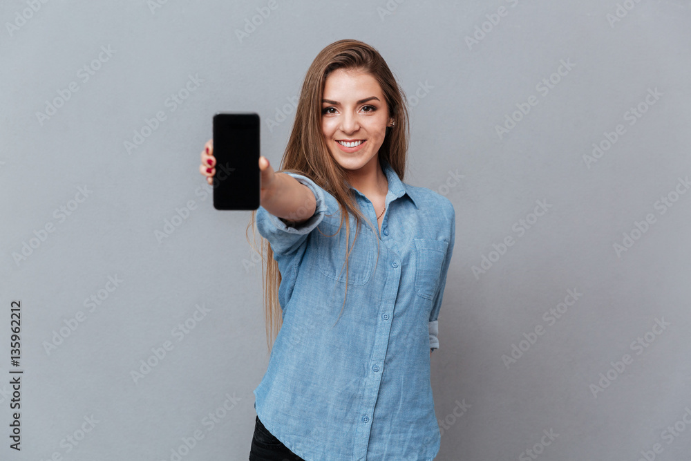 Naklejka premium Woman in shirt showing blank smartphone screen