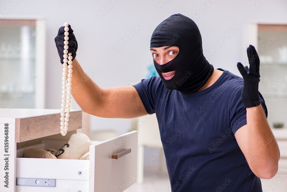 Robber wearing balaclava stealing valuable things Robber wearing balaclava stealing valuable things