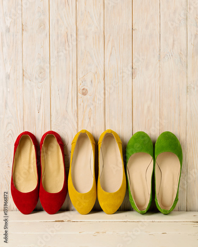 Red, green and yellow women's shoes (ballerinas) on wooden backg