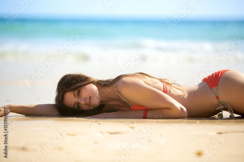 Beautiful young woman lying on sand beach