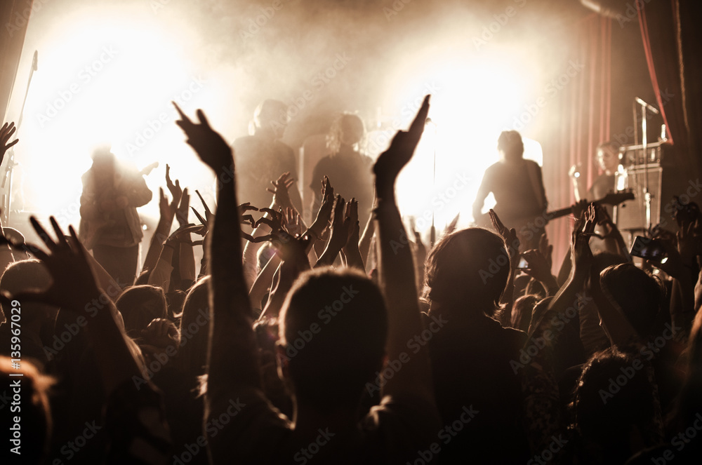 silhouettes of people at a concert in front of the scene in bright light