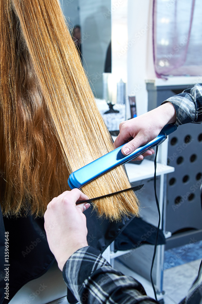 Φωτογραφία Professional hairdresser straightens model hair