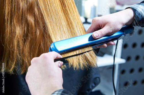 Canvas-taulu Professional hairdresser straightens model hair