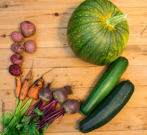 Harvest of fresh vegetables on wooden background. Top view. Potatoes, carrot, squash, peas, tomatoes, greens, beets, zucchini, tomatoes, peppers, onion, garlic, cucumber, dill.