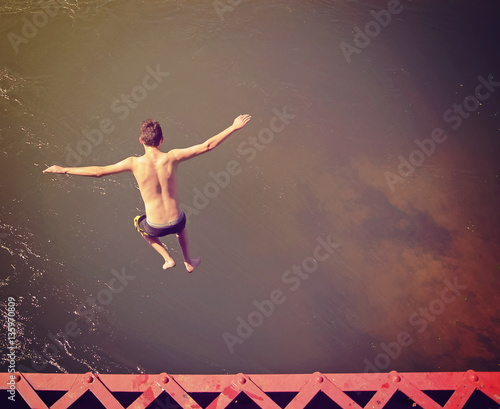 Wallpaper Mural a boy jumping of an old train trestle bridge into a river done with a retro instagram filter Torontodigital.ca
