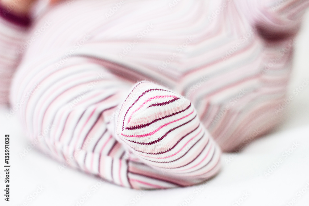 Newborn baby foot in pajamas, leg close-up. Infant lying on his back. Baby sleepers. Newborn baby foot in pajamas, leg close-up. Infant lying on his back. Baby sleepers.